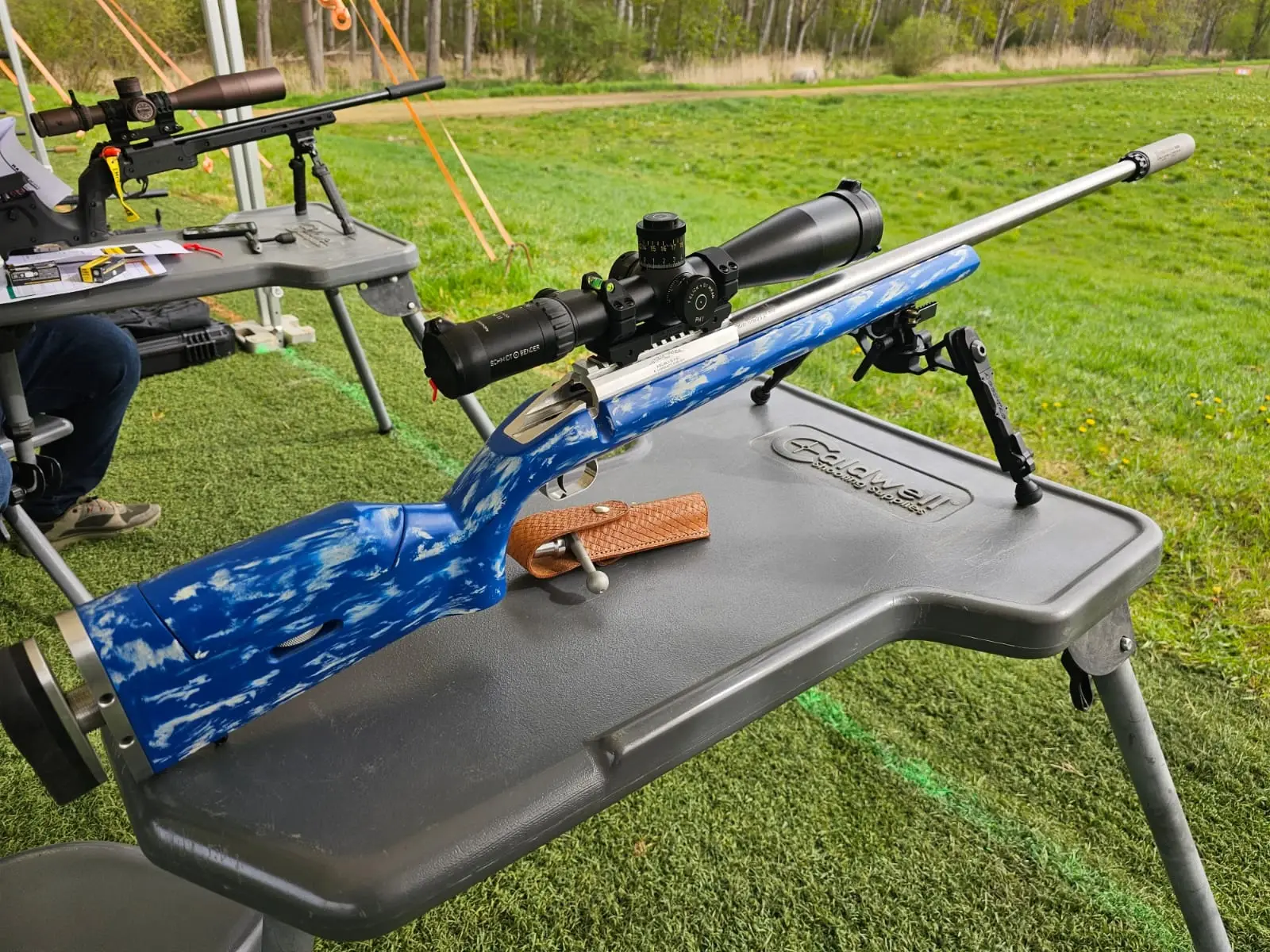 Rifle with a blue stock and a riflescope on a shooting bench