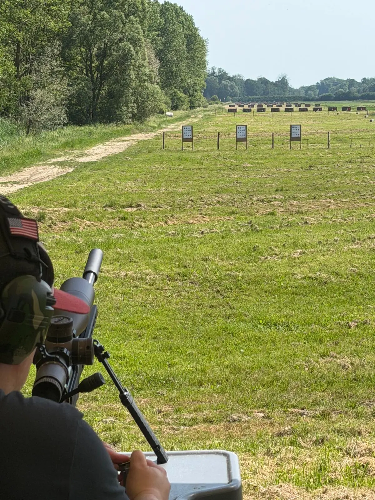 Looking downrange over a shooter and spotting scope towards the targets